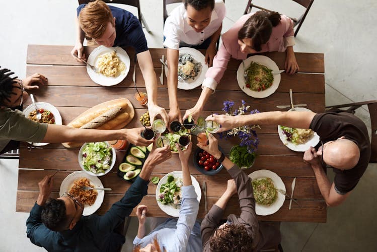 A group of friends toasting around a table full of food, sharing a meal on holiday