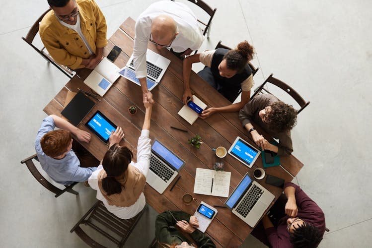 Group of friends planning a trip together around a table with laptops